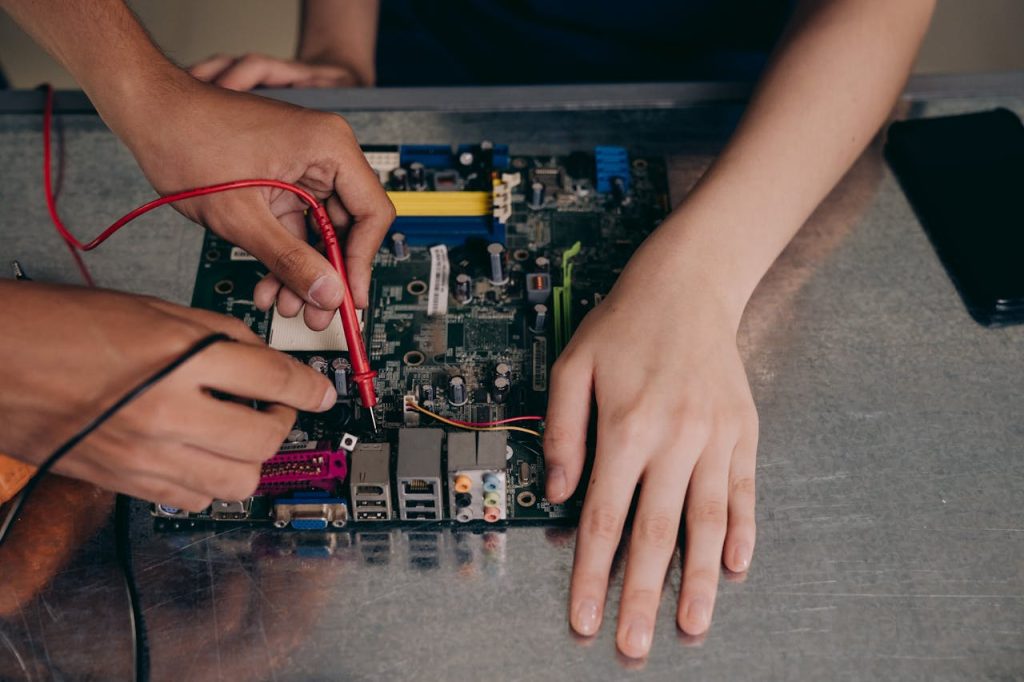 Hands working with electrical tester on motherboard, showcasing technical repair skills.